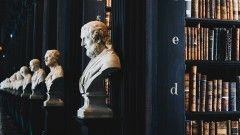 a line of marble busts along shelves of books